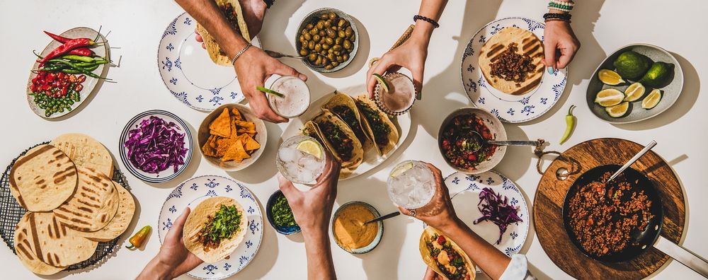 Mesa mexicana coletiva com vários pratos e pessoas se servindo